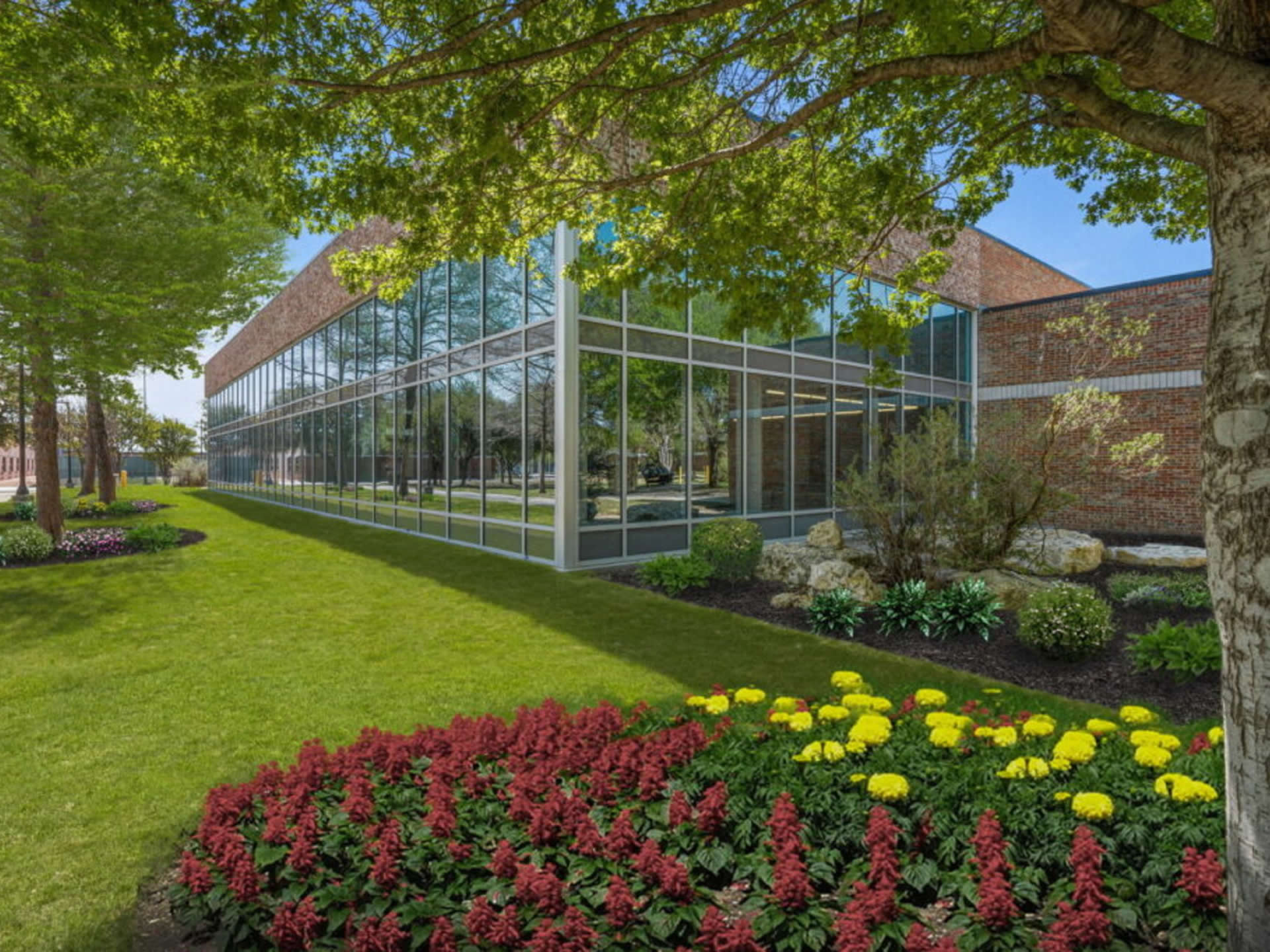 Glass building with trees and flowerbeds